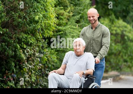 Vieux souriant, transport en fauteuil roulant senior dans le parc Banque D'Images