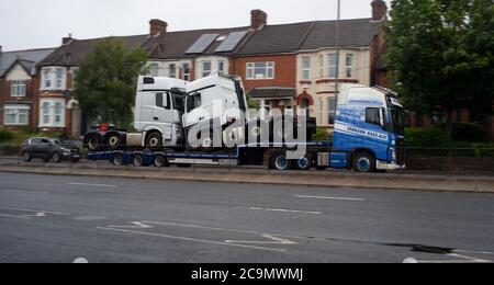 Un camion de transport Johnson transportant deux camions sur une remorque voyageant sur la route Millbrook Southampton vers Southampton Docks. Banque D'Images