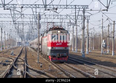 RÉGION DE LENINGRAD, RUSSIE - 09 AVRIL 2018 : locomotive électrique ChS7-068 avec un train de passagers à une jonction ferroviaire le jour d'avril ensoleillé Banque D'Images