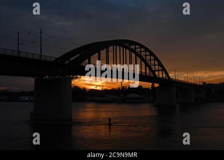 Le vieux pont Sava au coucher du soleil à Belgrade, Serbie. Le pont traverse la rivière Sava dans le centre de Belgrade et est silhoueté contre le ciel orange Banque D'Images