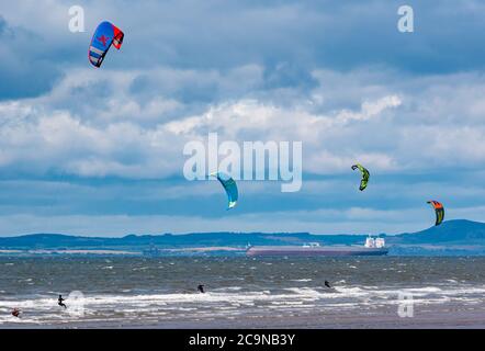 Kite Surfers kite surfant par temps venteux avec un pétrolier ancré à l'horizon à Firth of Forth, en Écosse, au Royaume-Uni Banque D'Images