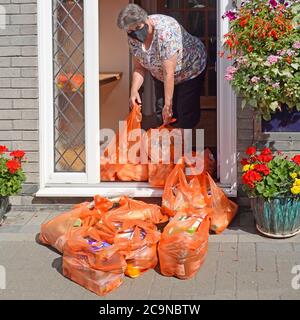 Sainsburys sacs d'épicerie en plastique par sac de livraison de conducteur Déplacé par retraité senior dans Covid 19 masque & Maintient une distance sociale au Royaume-Uni Banque D'Images