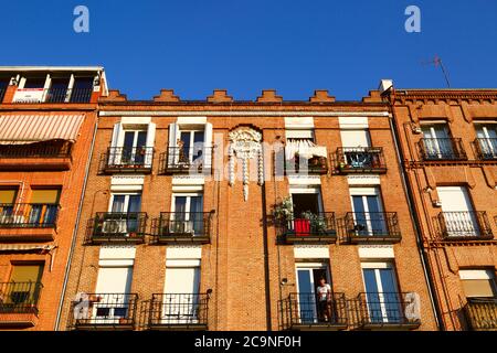 Homme sur le balcon de l'immeuble d'appartements datant de 1914 sur la Calle del Rosario près de Plaza San Francisco, quartier impérial, Madrid, Espagne Banque D'Images