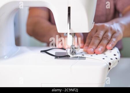 Homme mains couture d'un masque médical de visage à une machine à coudre. Faites-le vous-même, zéro gaspillage et coronavirus concepts. Banque D'Images