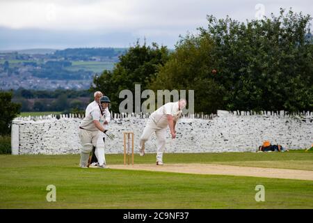 Un joueur de cricket de taille moyenne dans un village un match de cricket un jeu de quilles une livraison et être regardé par l'arbitre et le batteur non-frappant Banque D'Images