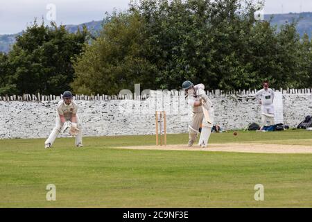 Batteur jouant un hors-route dans un match de cricket du village dans le West Yorkshire un samedi après-midi en août Banque D'Images