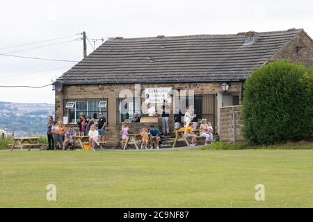 Les résidents du village de Kirkheaton dans le Yorkshire regardent un match de cricket depuis le club-House un samedi après-midi en août Banque D'Images