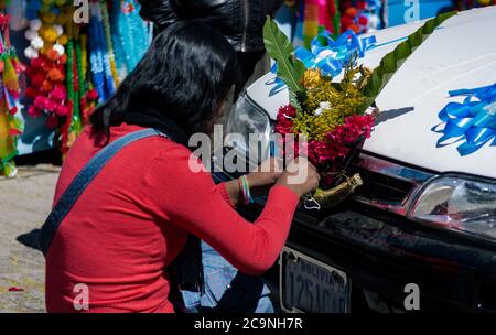 COPACABANA, BOLIVIE - 24 JUILLET 2016 : une femme non identifiée décore une voiture avec un bouquet coloré pour la tradition religieuse des voitures de bénédiction à côté de t Banque D'Images