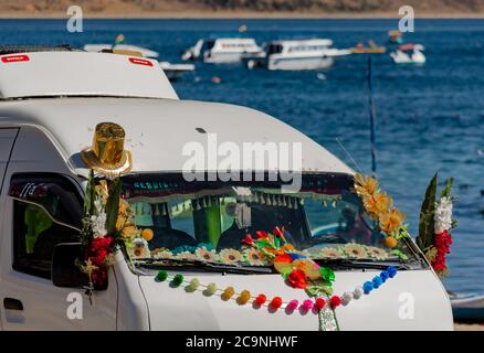 COPACABANA, BOLIVIE - 24 JUILLET 2016 : détail d'une fourgonnette décorée avec un bouquet religieux et coloré et des garnitures avec le lac Titicaca en arrière-plan. Co Banque D'Images