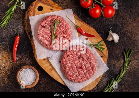 Hamburgers de bœuf frais, hachés et faits maison, sur planche à découper en bois, vue du dessus Banque D'Images