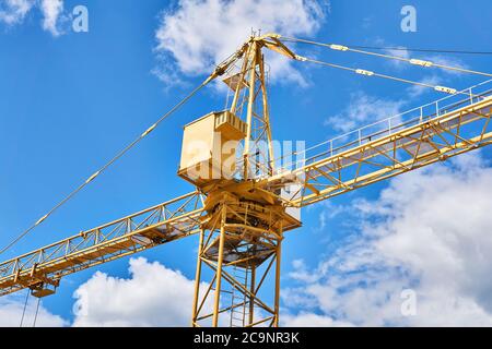 fragment d'une grue de tour de construction jaune contre un ciel bleu avec des nuages Banque D'Images