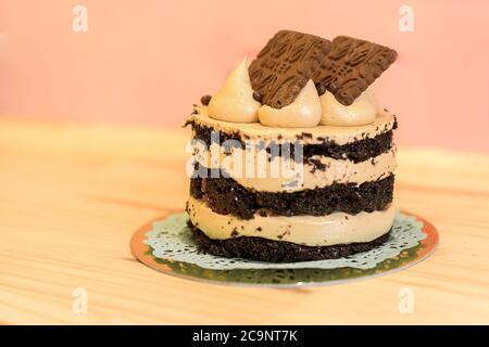 Gâteau au chocolat isolé avec crème et biscuits sur une table en bois. Fond rose. Concept de boulangerie. Gâteau savoureux et délicieux. Photo d'un cacao Banque D'Images