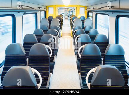 Habitacle du train de voyageurs avec sièges vides sur deux rangées, en mouvement, dans une lumière vive. Voyage en train en Allemagne. Transports en commun modernes. Pas de voyageurs Banque D'Images