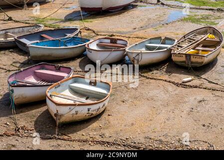Des rangées de bateaux à rames assis dans la boue à marée basse à Old Leigh, Leigh on Sea, Essex, Royaume-Uni. Chaînes d'amarrage roueuses et algues vertes. Bateaux, dinghies Banque D'Images