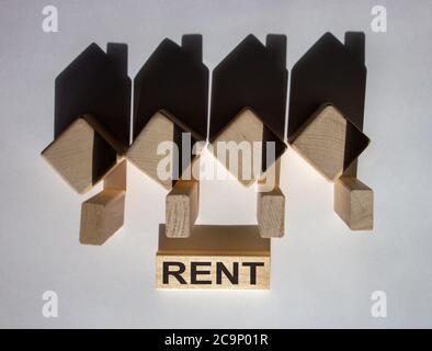 Maisons créées par des ombres à partir de cubes en bois. Le mot « rent » sur un bloc de bois. Banque D'Images