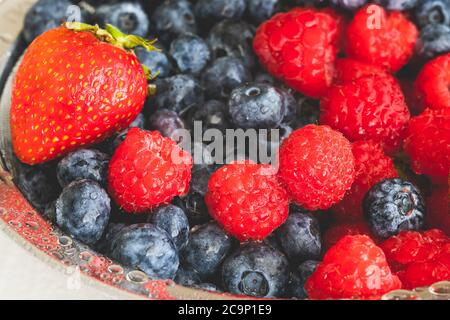Fraises fraîches mûres lavées, bleuets, framboises en passoire gros plan sur fond blanc Banque D'Images
