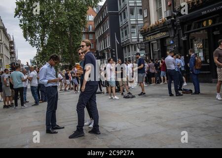 Les employés de la ville apprécient de boire au pub Sugarloaf tout en dehors socialement distancé le vendredi soir d'été sur Queen Street, Londres, EC4 Banque D'Images