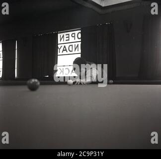 Années 1950, historique, un jeune homme jouant au snooker dans une cabane dans un camp de vacances britannique, Angleterre, Royaume-Uni. En cette époque, les camps de vacances en bord de mer étaient très populaires en Grande-Bretagne et avaient de nombreuses installations de loisirs pour les clients, y compris des foires de funkers, des piscines, un vert d'exercice et une piscine/snooker. Banque D'Images