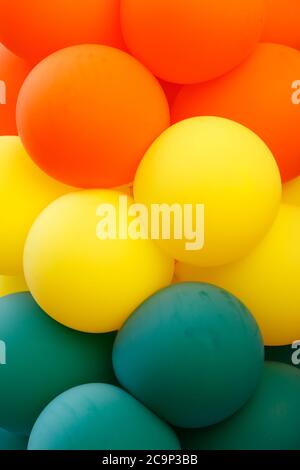 Gros plan d'un groupe de ballons de couleur verte, jaune et orange formant des rubans dans chaque couleur. Banque D'Images