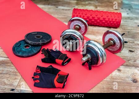 Haltères, gants d'entraînement et rouleau en mousse à l'étage d'un appartement. Objets d'entraînement à domicile Banque D'Images