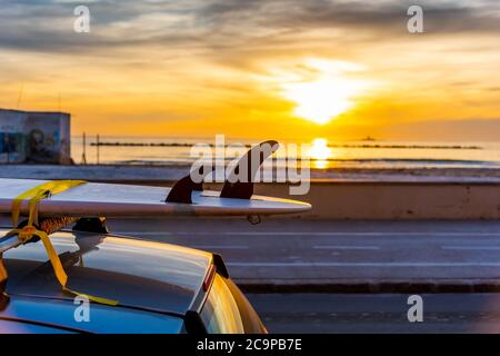 Surfboard sur le toit d'une voiture au coucher du soleil, au bord de la mer Banque D'Images