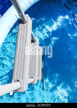 Échelle de piscine grise vue d'en haut par une journée ensoleillée. Piscine dans une cour résidentielle Banque D'Images