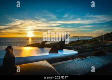Surfboard sur le toit d'une voiture au coucher du soleil, au bord de la mer. Banque D'Images