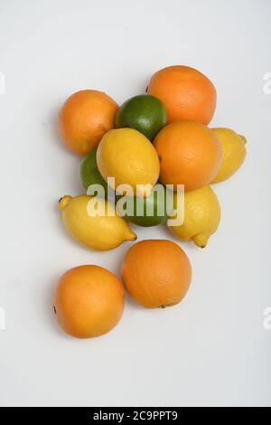 FÊTE DES AGRUMES : une collection d'oranges, de limes et de citrons est disposée dans une couche plate sur un fond blanc pur. Banque D'Images