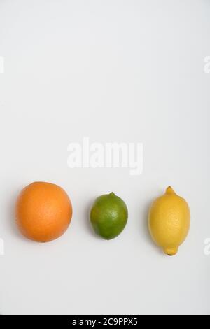 FÊTE DES AGRUMES : une collection d'oranges, de limes et de citrons est disposée dans une couche plate sur un fond blanc pur. Banque D'Images