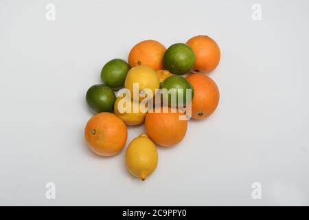 FÊTE DES AGRUMES : une collection d'oranges, de limes et de citrons est disposée dans une couche plate sur un fond blanc pur. Banque D'Images