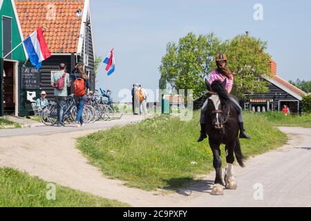Jeune fille à cheval dans un village touristique avec des maisons et des magasins à Zaanse Schans, Zaandam, pays-Bas Banque D'Images