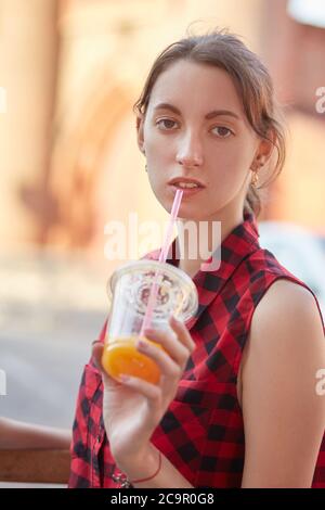 Jeune femme en chemisier rouge assis dans street cafe cocktail boissons looking at camera Banque D'Images