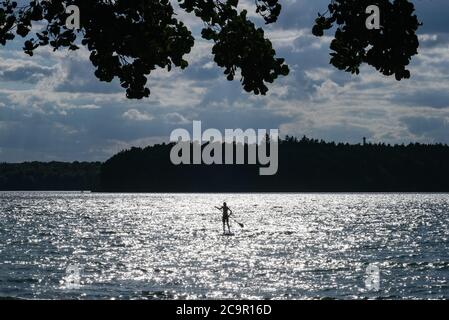 Neuglobsow, Allemagne. 29 juillet 2020. Un pagayeur debout sur le Großer Stechlinsee en fin d'après-midi avec le soleil bas dans le ciel créant les paillettes sur l'eau. Il fait partie du parc naturel de la terre de Stechlin-Ruppiner, appartient au district du lac de Rheinsberg dans la zone naturelle de la Neustrelitzer Kleinseenland, est connu pour sa bonne qualité de l'eau et à 70 mètres est le lac le plus profond de Brandebourg. Credit: Jens Kalaene/dpa-Zentralbild/ZB/dpa/Alay Live News Banque D'Images