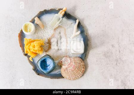 Vue de dessus de divers produits cosmétiques dans des pots disposés sur une table avec des coquillages et de la pierre minérale Banque D'Images