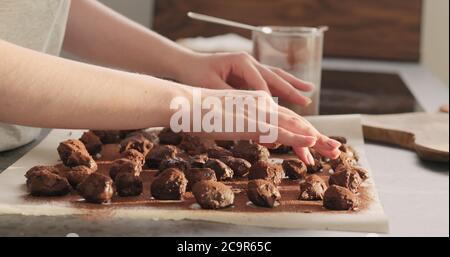 jeune femme roulant de truffes au chocolat en poudre de cacao à la maison kictchen Banque D'Images