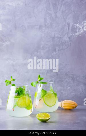 Cocktail de mojito au citron vert et à la menthe en verre. Deux verres de mojito sur fond gris. Cocktail rafraîchissant à la menthe et au citron vert. Eau perfusée Banque D'Images