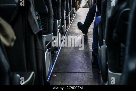 Sièges de bus vus de la rangée arrière, un passager a son pied dans l'allée. Banque D'Images