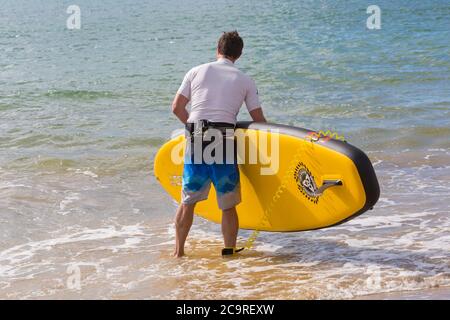 Poole, Dorset Royaume-Uni. 2 août 2020. Météo au Royaume-Uni : belle journée chaude et ensoleillée sur les plages de Poole, les températures grimpent et les amateurs de soleil affluent en bord de mer pour profiter du temps ensoleillé. Paddleboarder entrant dans la mer. Crédit : Carolyn Jenkins/Alay Live News Banque D'Images