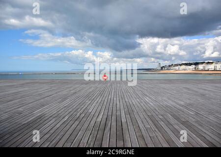 Une canne de pêche sans surveillance est restée sur la promenade de Hastings Pier, en direction de l'ouest vers St.Leonards, Bexhill, et Eastbourne, Sussex, Angleterre, Royaume-Uni. Banque D'Images