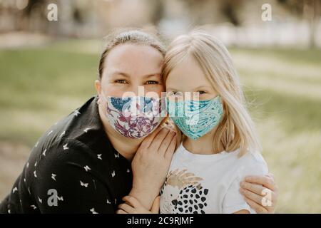 La mère et la fille portent des masques en tissu pendant la pandémie COVID-19 du virus corona qui s'enserre à l'extérieur Banque D'Images