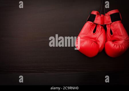 Deux gants de boxe rouges suspendus sur un fond noir dans le coin du cadre, placez pour le texte Banque D'Images