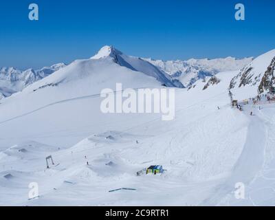 Paysage d'hiver avec des pistes de montagne enneigées et des pistes avec des skieurs profitant de la journée ensoleillée au printemps à la station de ski Stubai Gletscher, Stubaital, Tyrol, Banque D'Images