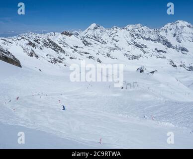 Paysage d'hiver avec des pistes de montagne enneigées et des pistes avec des skieurs profitant de la journée ensoleillée au printemps à la station de ski Stubai Gletscher, Stubaital, Tyrol, Banque D'Images