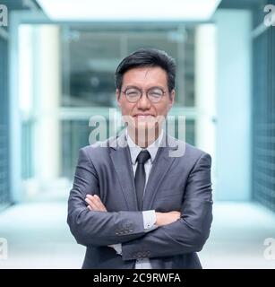 Portrait d'un homme d'affaires chinois souriant en costume d'affaires, regardant l'appareil photo Banque D'Images