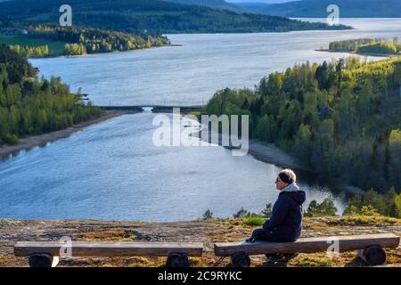 Vue sur Vikbotten une partie de la haute côte dans Vasternorrland Suède avec une femme prenant le repos sur un banc en bois devant et un pont au-dessus d'une entrée i Banque D'Images