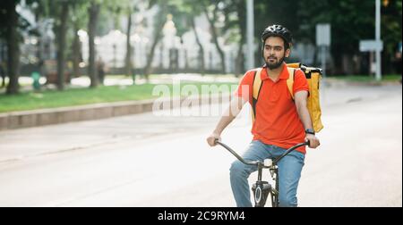 Portrait de messager masculin sur vélo avec sac à dos. Jeune homme en casque sur la route Banque D'Images