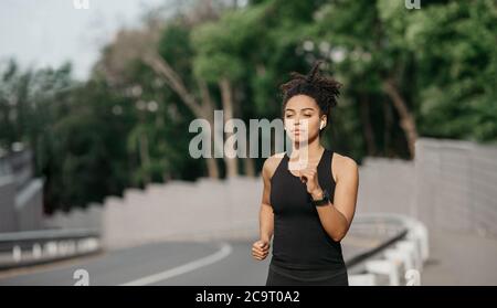 Femme en forme et en bonne santé. Une jeune fille afro-américaine concentrée qui s'exécute sur une passerelle Banque D'Images