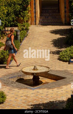 Séville, Espagne 07/12/2010: Une femme touriste avec un sac à dos marche dans la cour de l'Alcazar de Séville par une journée ensoleillée. Il y a un artistique Banque D'Images