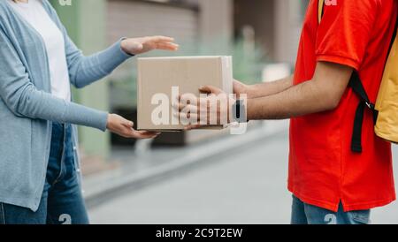 Service de quarantaine et de livraison en ligne. Une femme prend le colis du coursier avec une montre intelligente et un sac à dos Banque D'Images