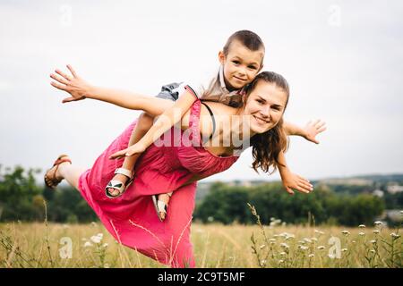 Une mère célibataire s'amuse avec son fils dans la nature. Une mère fait monter un enfant sans père. Pas une famille complète. Le thème de la maternité et de l'enfance Banque D'Images